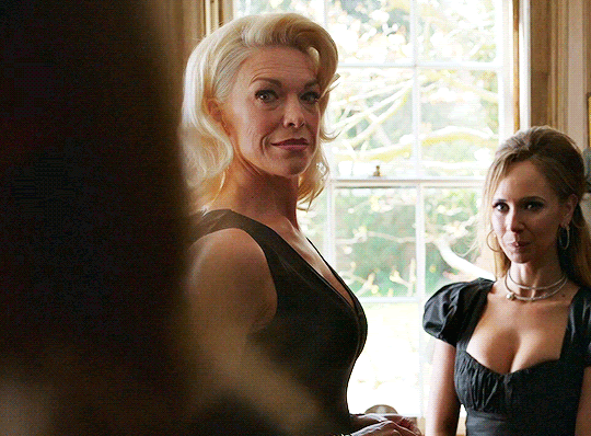 Rebecca turns to smile, with Keeley in the background grinning mischieveously.