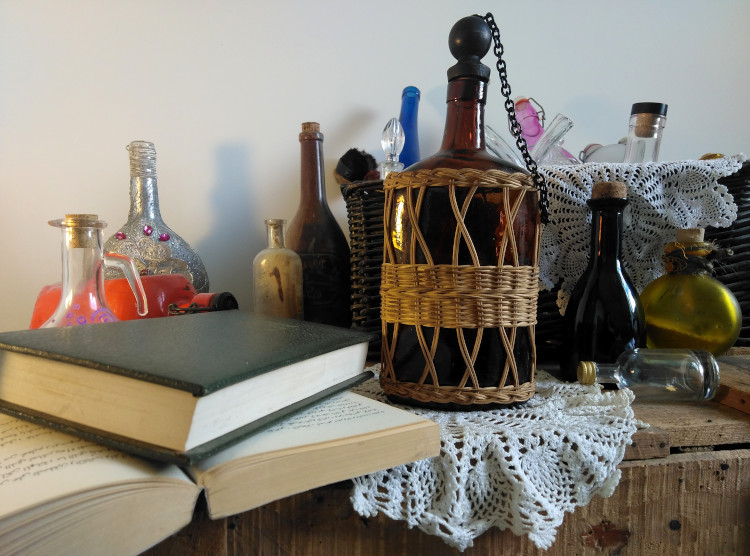 plein de jolies bouteilles disposées sur des napperons sur une caisse en bois, et qui n'attendent que de libérer leurs histoires! au premier plan à gauche, deux livres