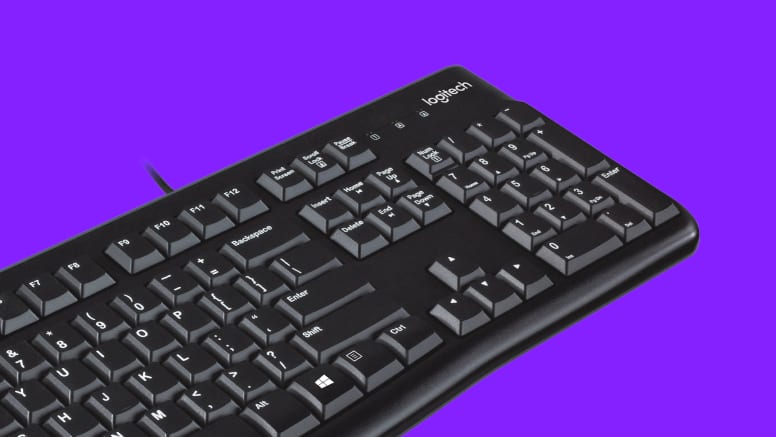 Vista lateral del teclado Logitech K120, mostrando sus patas ajustables y el diseño resistente a derrames.