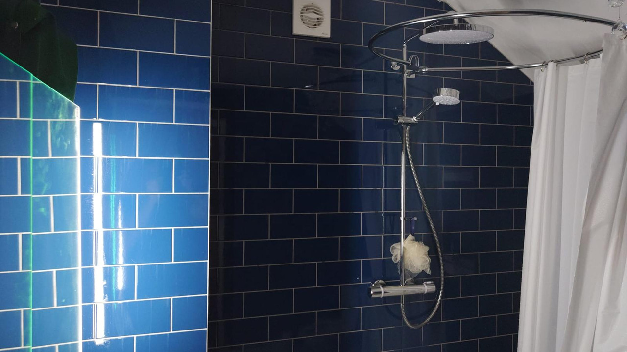Premium bathroom shower area with navy wall tiles and chrome shower