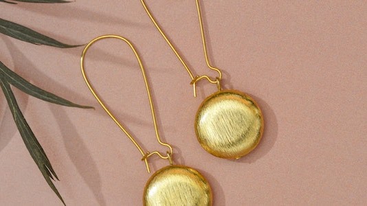 A pair of drop earring placed at a table