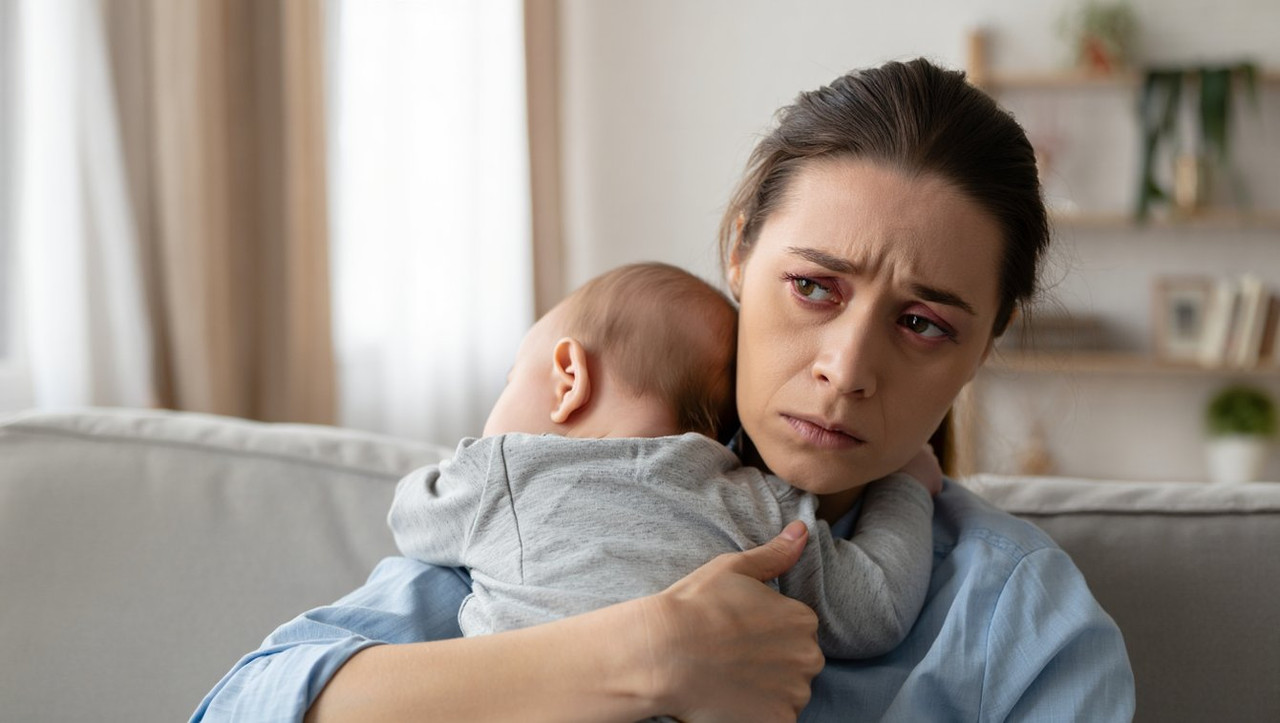 Уставшая мама с ребенком на руках испытывает материнское выгорание