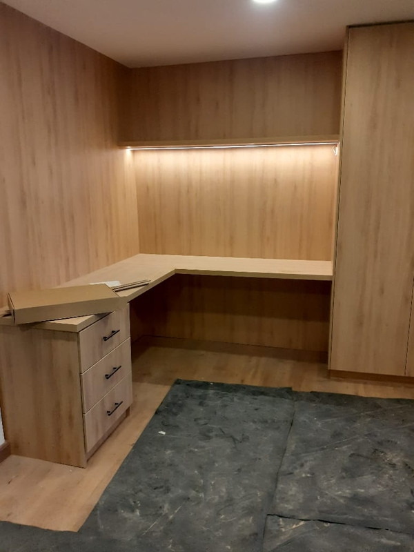 Oficina en casa con escritorio en L y paneles de madera