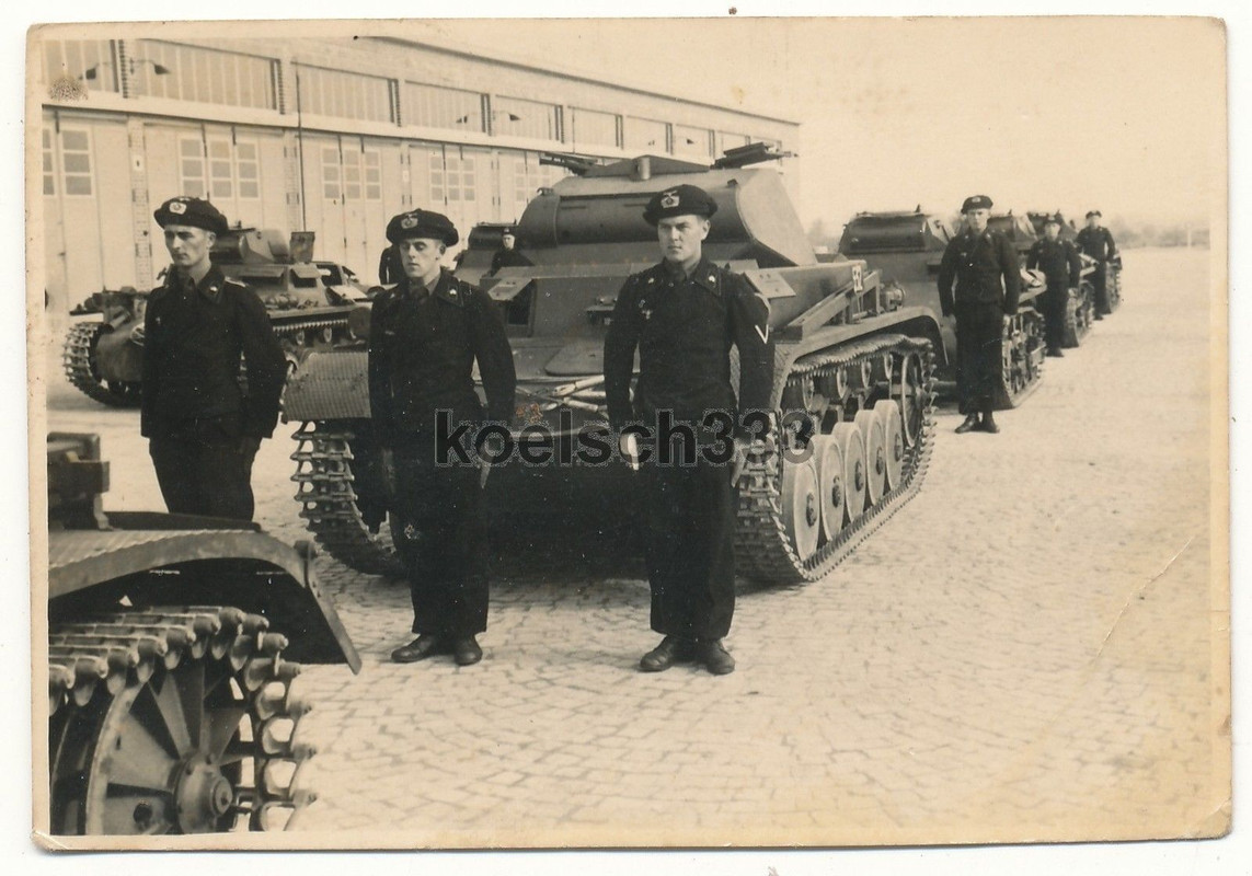 Panzermänner mit Panzerschutzmützen vor Panzer I