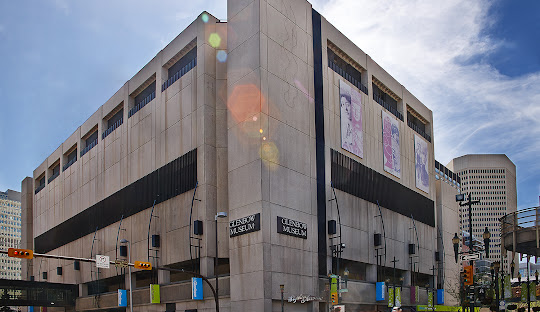A large building featuring a prominent window on its side, showcasing modern architectural design.