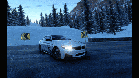 White BMW sports car drifting on a snowy mountain road at dusk, headlights on, with snow-covered pine trees and yellow road signs in the background. The scene feels dynamic and energetic.