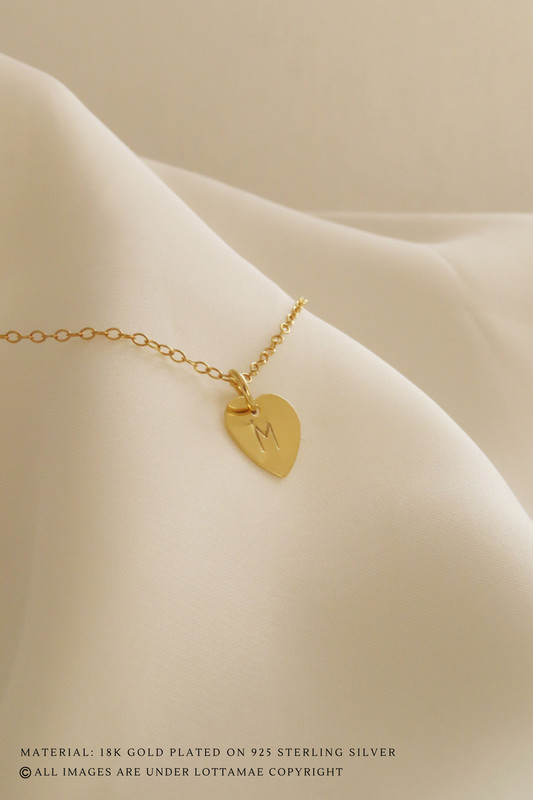 Este delicado collar de corazón personalizable es la forma perfecta de mostrar tu personalidad. Fabricado en plata de ley 925 y chapado en oro de 18 quilates, este collar atraerá todas las miradas allá donde vaya. La inicial que elijas se estampará a mano en el disco, convirtiéndolo en una pieza de joyería totalmente única que podrás lucir con orgullo. Tanto si eliges tu propia inicial como un recuerdo especial de alguien cercano, este collar es una forma maravillosa de expresar quién eres. Perfecto para llevar a diario, añadirá un toque de elegancia a cualquier atuendo. Añade hoy mismo a tu colección esta hermosa pieza de joyería personalizada.