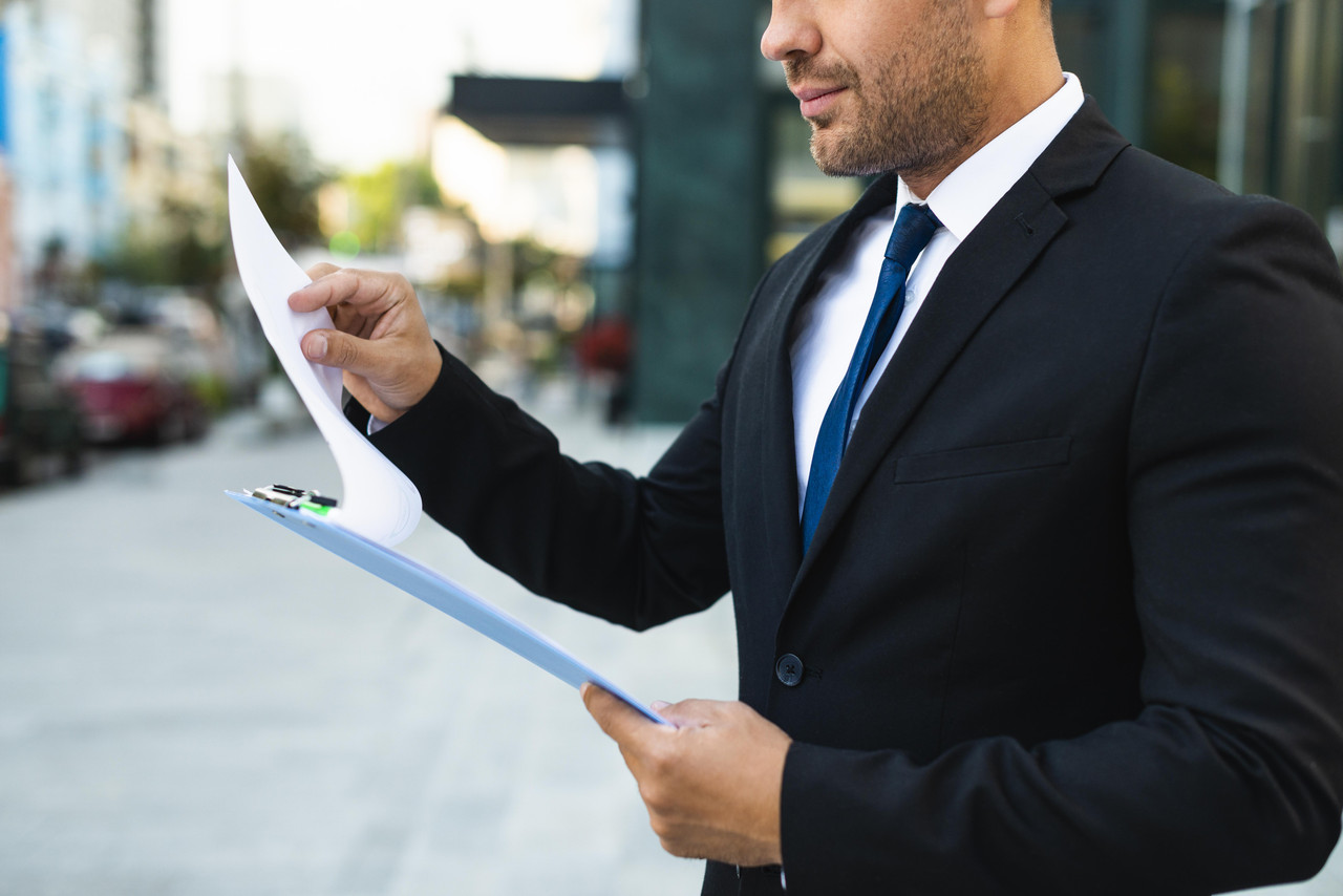 side view business man reading from clipboard