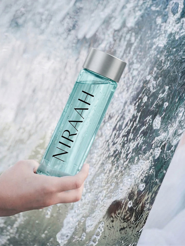 A hand gracefully holding a Niraah bottle near a delicate water splash