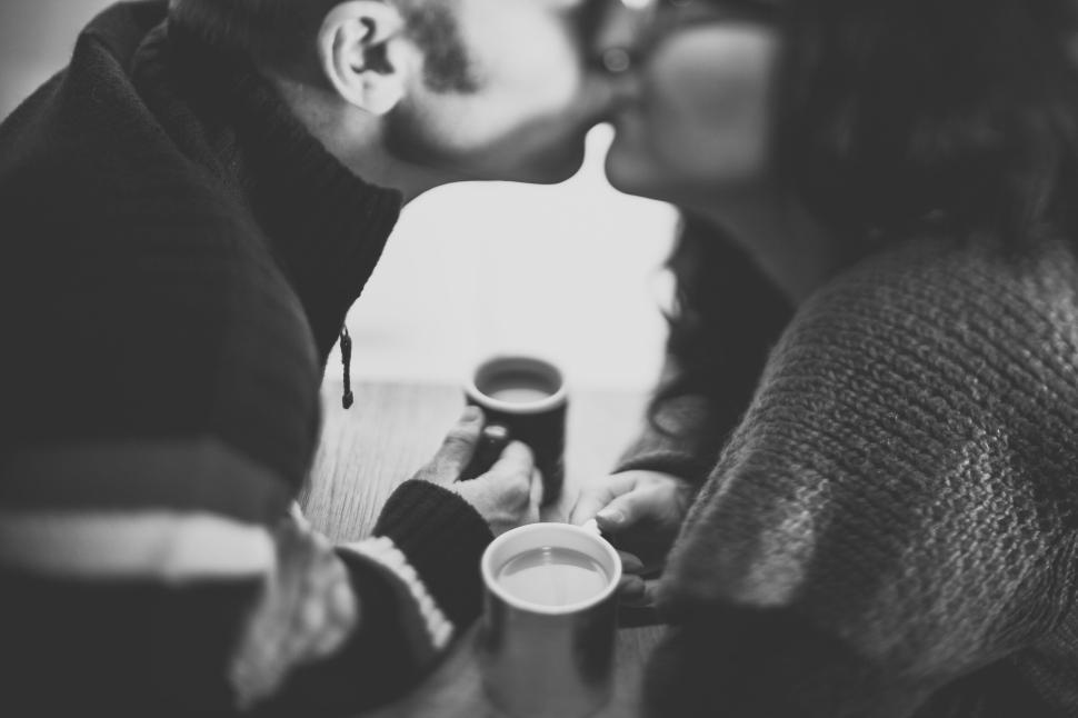 couple-sharing-a-kiss-over-coffee-at-a-cozy-table