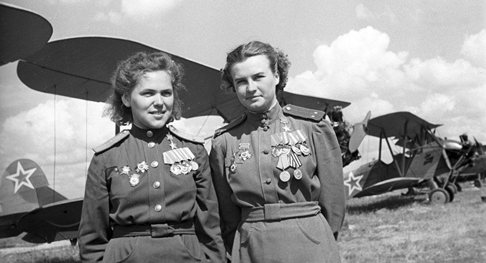 Rufina Gásheva, izquierda y Natalia Meklinm, derecha, posando frente a aviones Polikarpov Po-2 biplanos
