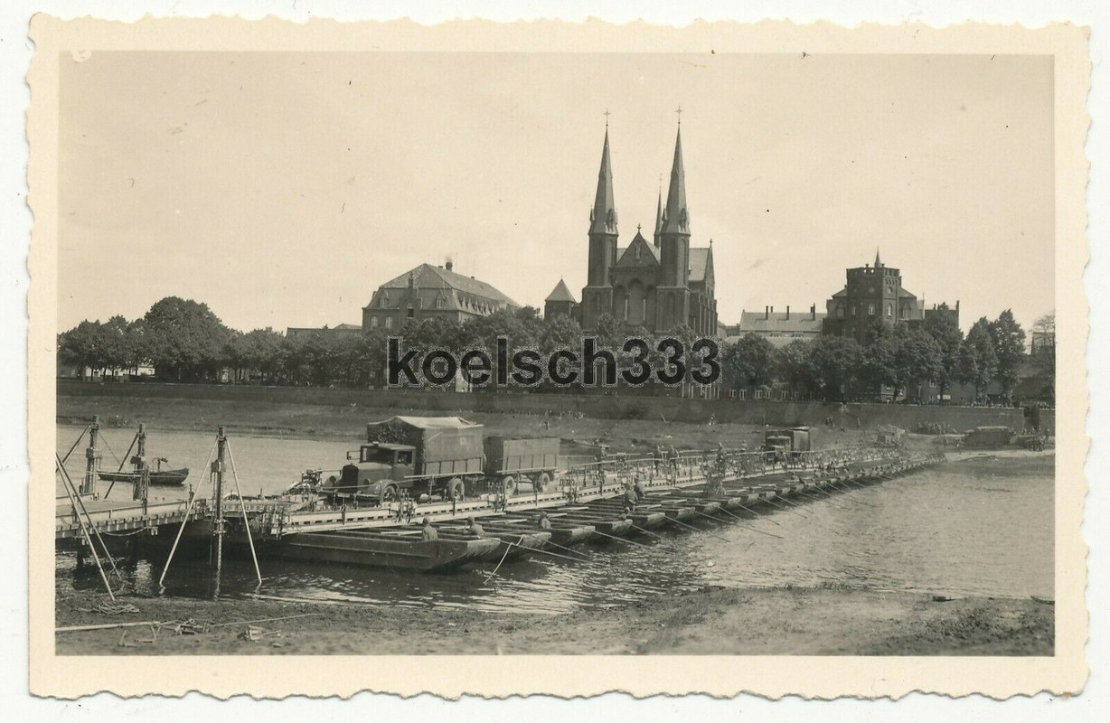 Foto LKW mit Anhänger der Wehrmacht auf einer Kriegsbrücke vor einer Kirche