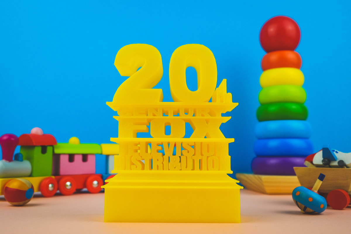 20th Century Fox Logo in yellow colors in a light blue and soft pink background. There are wooden toys for a decorative.