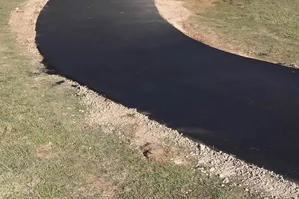 Fresh asphalt pathway with smooth curve through residential lawn