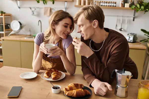stock-photo-young-couple-joyfully-shares-breakfast-croissants-warm-drinks-bright-kitchen