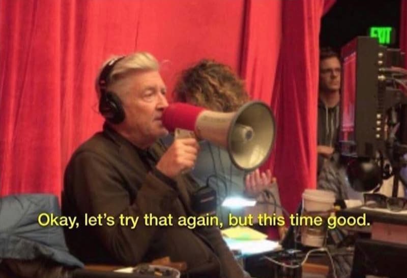 David Lynch with a megaphone, sitting. The caption says OK, Let's Try It Again, But This Time Good.