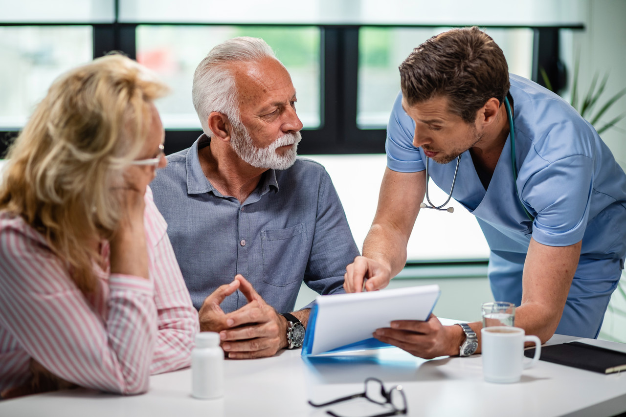 serious doctor discussing with senior couple about their medical documents appointment clinic (1)