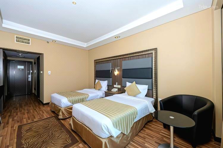 غرفة مريحة بسريرين في Pearl Swiss Hotel Dubai، بتصميم أنيق وأجواء دافئة تناسب العائلات أو المسافرين مع الأصدقاء.