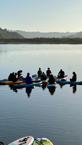 Grupo sentado sobre las tablas de SUP en el río Rapel al atardecer
