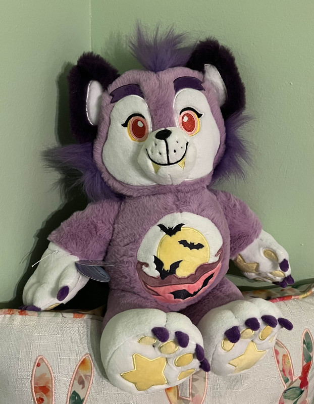 A purple carebear-style plush of a wolf