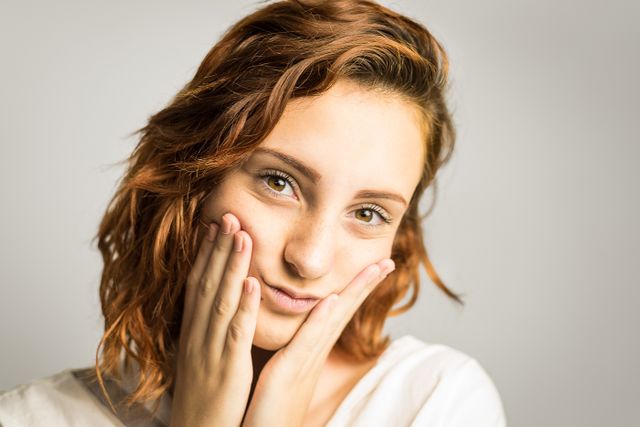  a woman holding her face in her hands showing HA changes as we age, but the changes are not as simple as losing it completely.