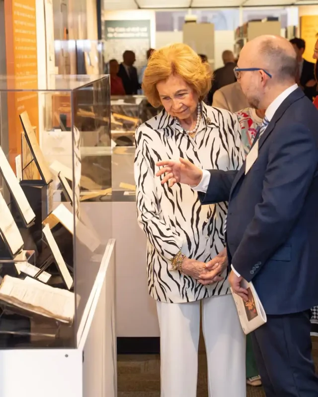 reina sofia posa con blusa de cebra pantalon blanco bolso de media luna y salones blancos frente a l
