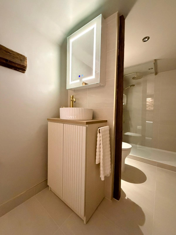 Illuminated vanity and shower view in rustic bathroom