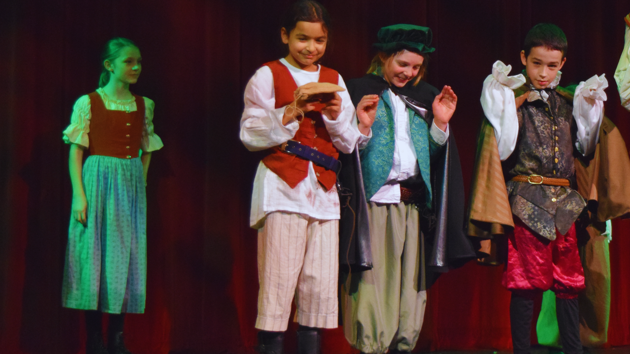 Four children in costumes on a stage