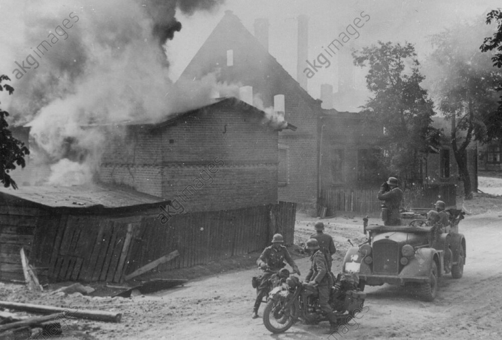 Der Offizier steht in seinem Kübelwagen (mittlerer Einheits-Pkw) und fotografiert, dasvor zwei Krads