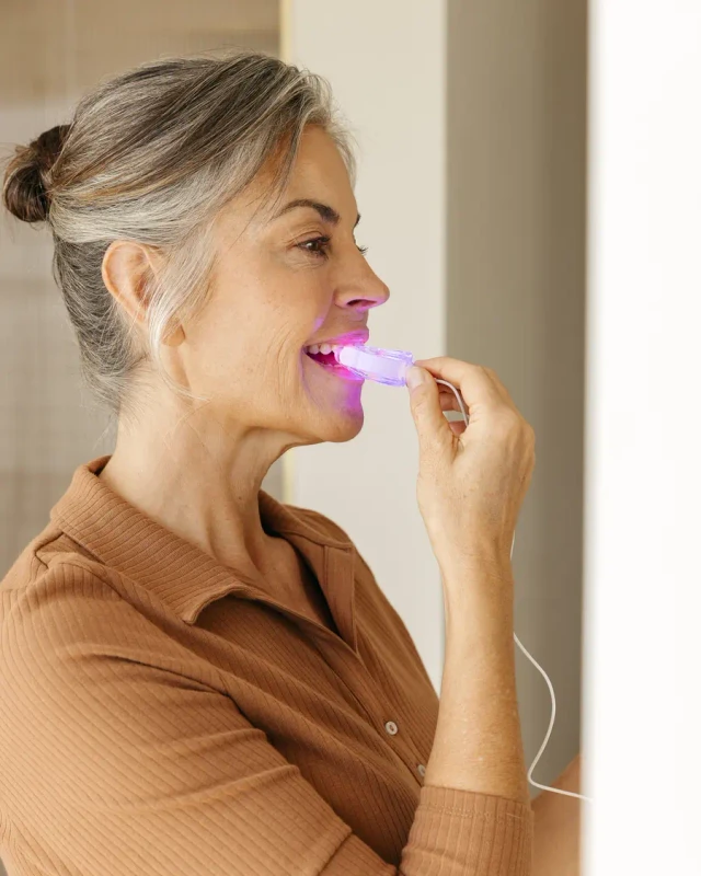 Woman using the Novaa Oral Care Pro light therapy device at home