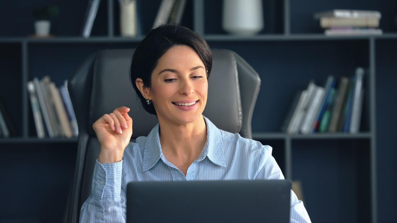 Empresária feliz a trabalhar no seu computador portátil num escritório moderno