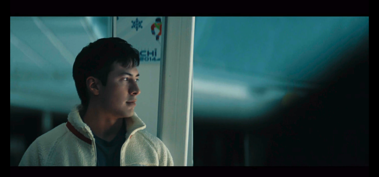 shane, framed from the chest up, fills the left side of the image. he's facing towards the camera and looking to the right of the image. the back of ilya's shoulder fills the right side of the image.