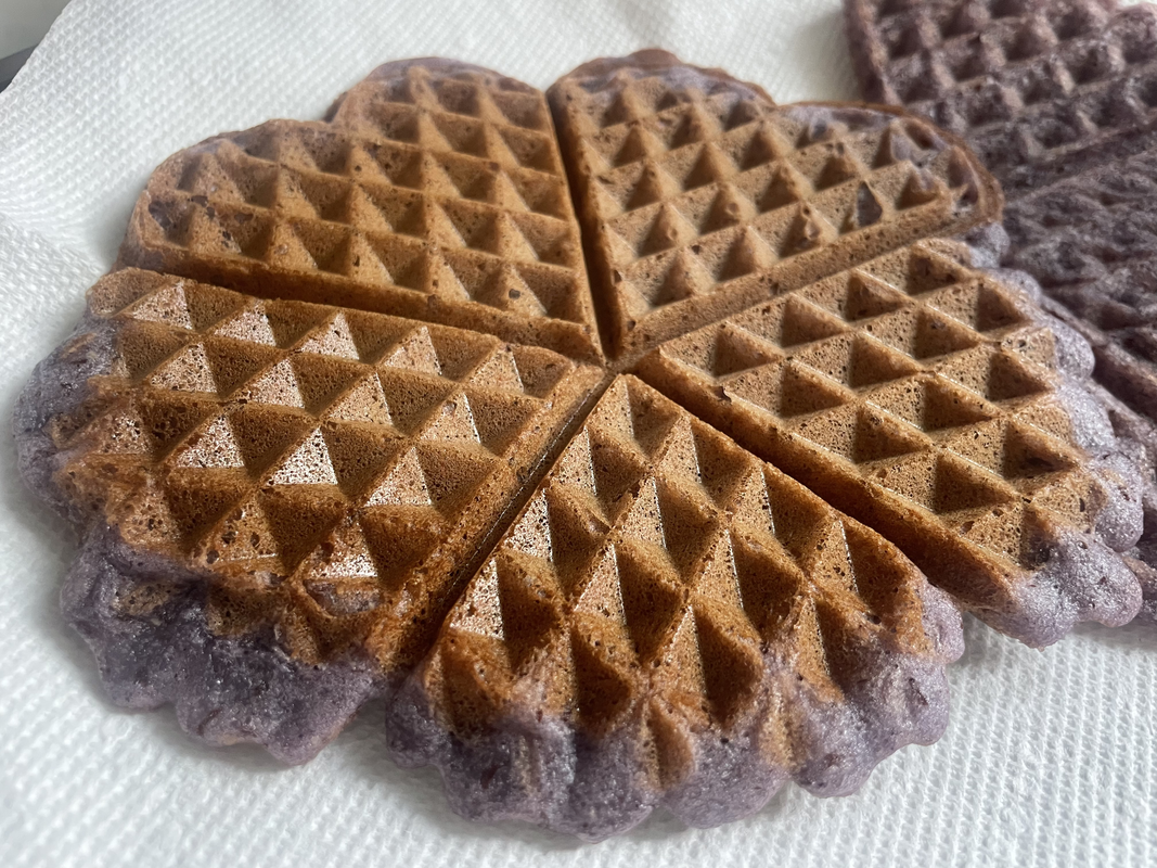 A photo of a very crispy and browned ube waffle with five parts that each look a little like a heart.