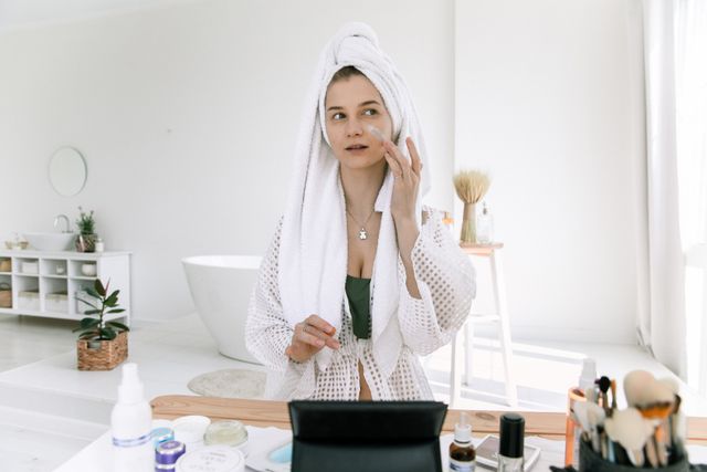 a girl prepping her skin before makeup with moisturizer, sunscreen and primer 