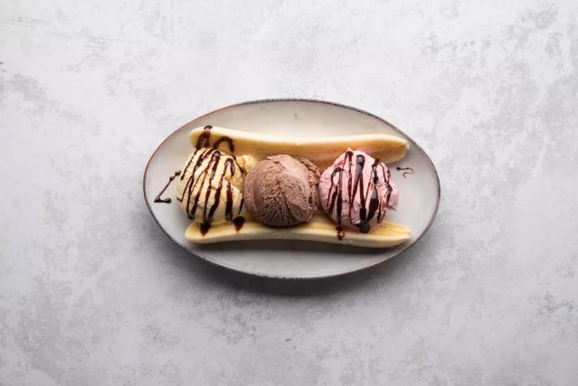 banane i sladoled na tanjiru preliveni cokoladom za banana split