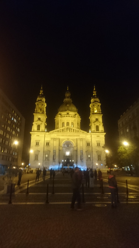 Front of the basilica of St. Stephen.  It is a neo-classical basilica.  There are people walking in front of it.