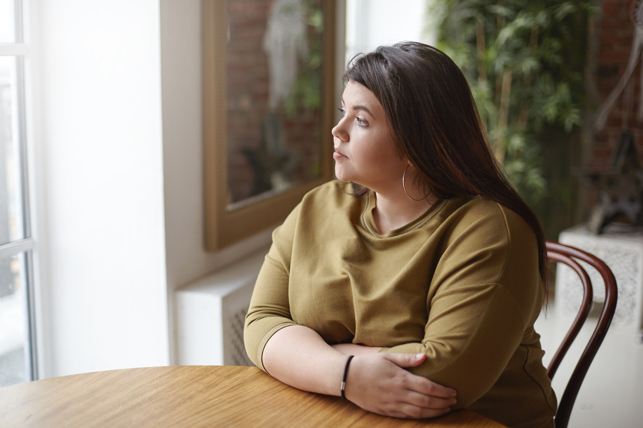 loneliness concept young brunette plus size woman with black hair sitting cafe table feeling lonely