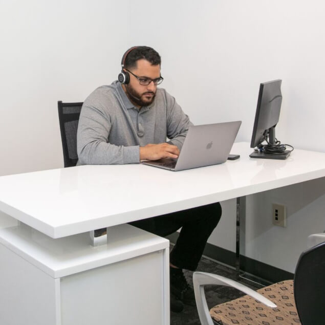 Multiple rows of green chairs positioned at height-adjustable desks