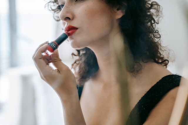 a woman applying lipstick to according to the fall makeup trends 