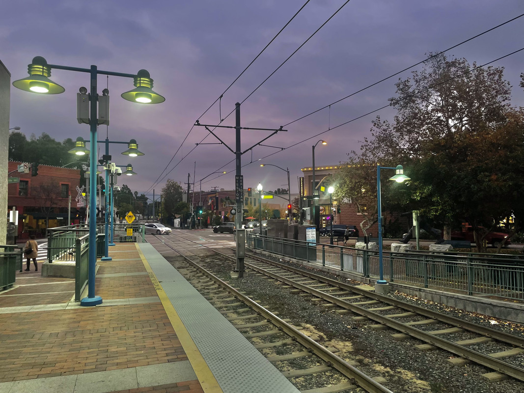 A photo of a train station with a very purple sky behind it.
