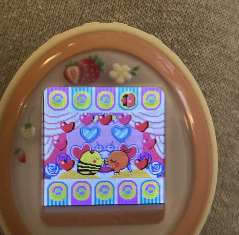 close up photograph of a tamagotchi plus color device. memetchi and simasimatchi are kissing