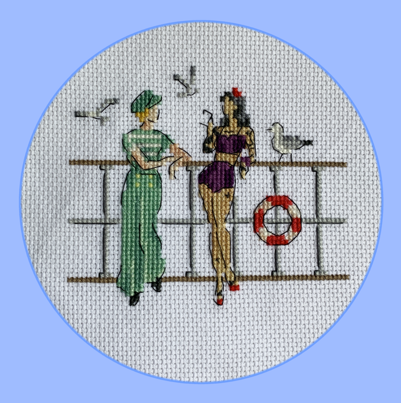 Embroidered artwork of Ed and Stede on the pier, leaning on the railing. Stede is wearing green sailor-style pants, a green and white striped top, and a green sailor cap. Ed is wearing her purple bikini. There is a seagull on the railing and two seagulls in the sky.