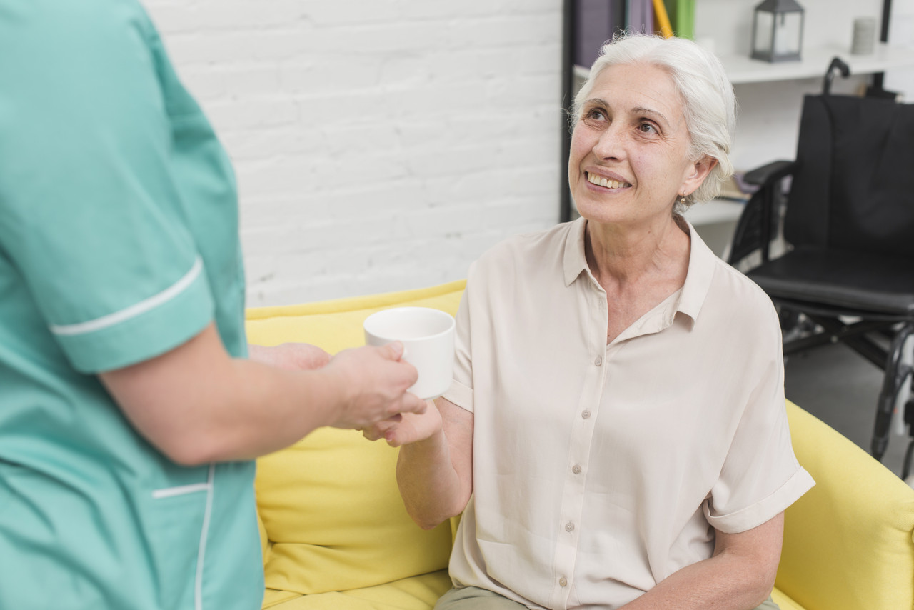 close up female nurse serving coffee senior woman
