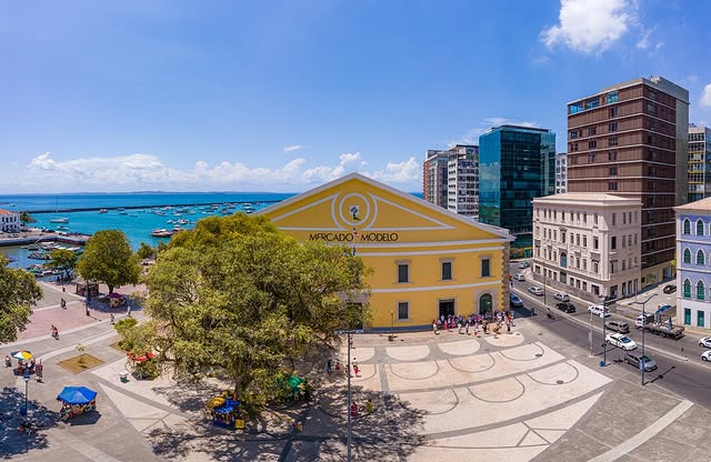 Fachada do Mercado Modelo com barcos ao fundo na Baía de Todos-os-Santos.