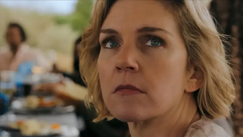 still frame from pluribus showing Carol outside at a group gathering. She is there with 11 other “unique” individuals immune to the hivemind and their family/friends/handlers who are part of the same collective conscious as carol’s “pirate lady” friend Raban