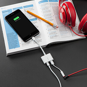 Adaptador Belkin Rockstar conectado a un iPhone, con audífonos y cable de carga.