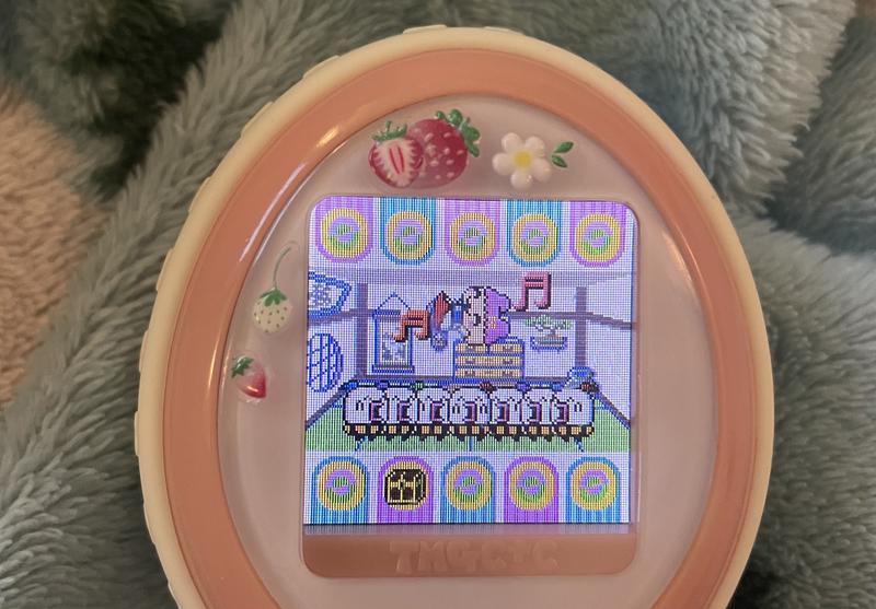 close up photograph of a tamagotchi plus color device. chamametchi is dressed as Snow White and being thrown up in the air by 7 shirotamas