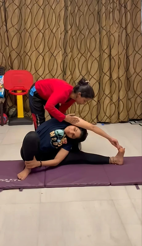 Yoga trainer guiding a client at home in Delhi