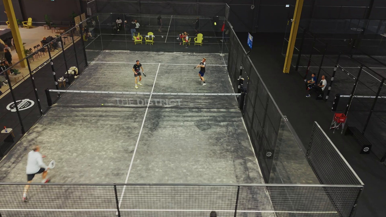 Overhead view of a glass-walled padel court in play at The District in Mississauga