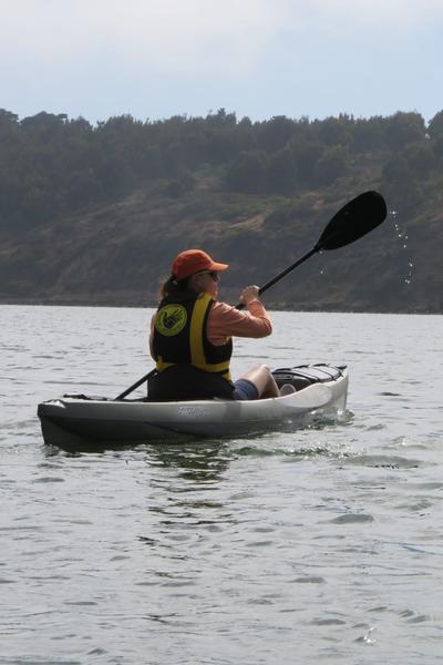 Persona remando en kayak con los cerros del río Rapel de fondo